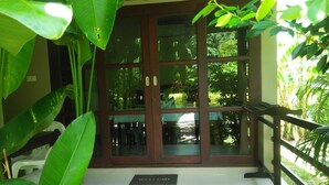 A hotel entrance with a glass door, a "Welcome" mat, and a view of greenery outside. - Bang Po Hut (Koh Samui)
