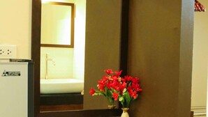 A bathroom with a white sink, a mirror, and a vase with red flowers. - Bang Po Hut (Koh Samui)