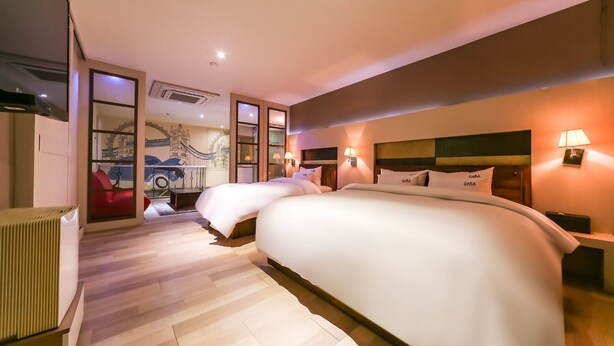 A modern hotel room with a large bed, two bedside tables with lamps, a red chair, and a wall mural. - STAY GONGDAM  (Changwon)