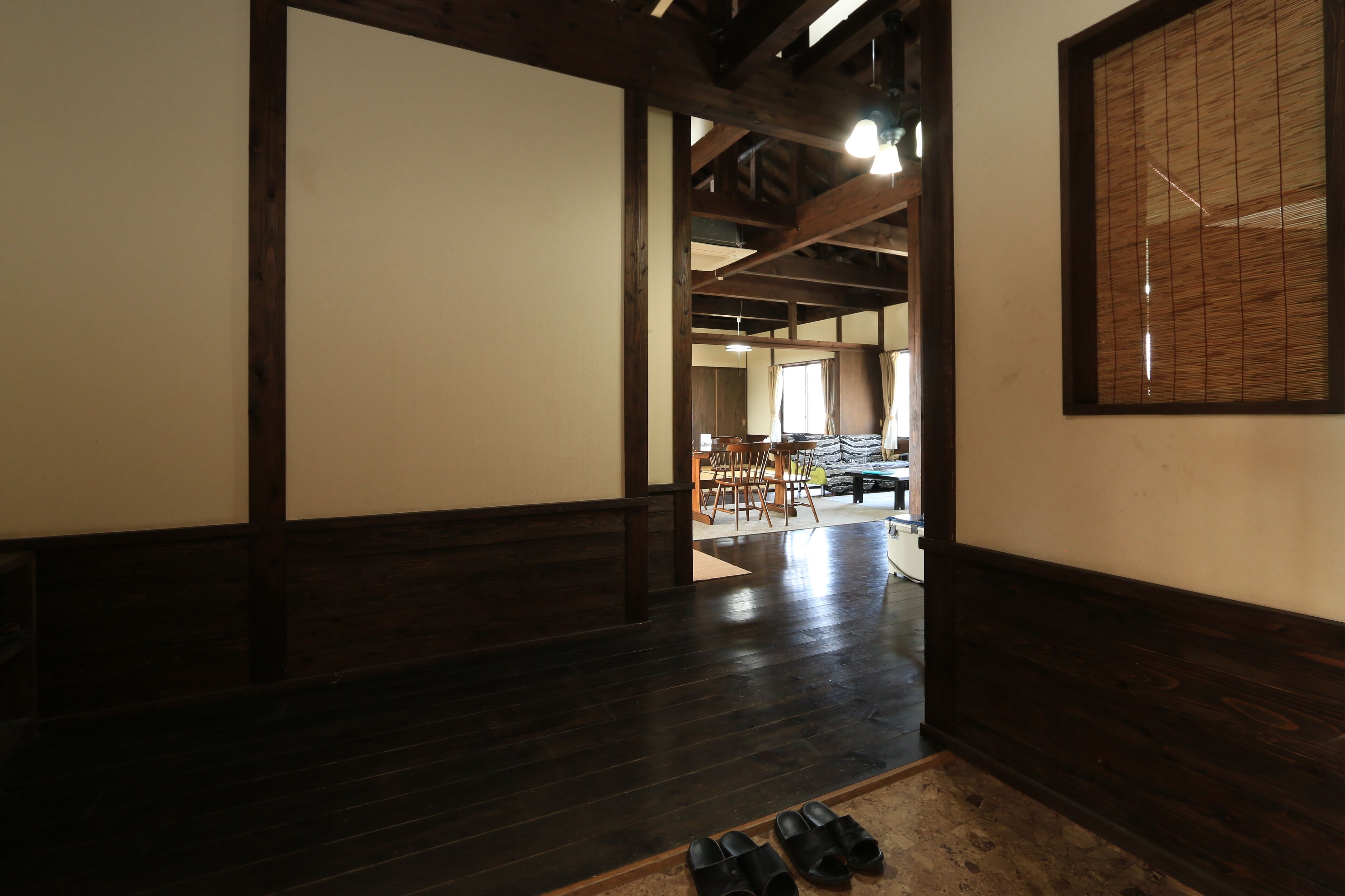 A room with dark wooden flooring, a large window with a view, and a traditional Japanese sliding door.