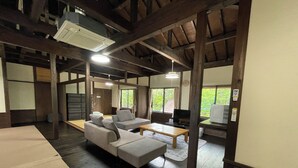 A traditional-style room with tatami mats, a low wooden table, and a sofa. - Kurasako Onsen Sakura (Minamioguni)