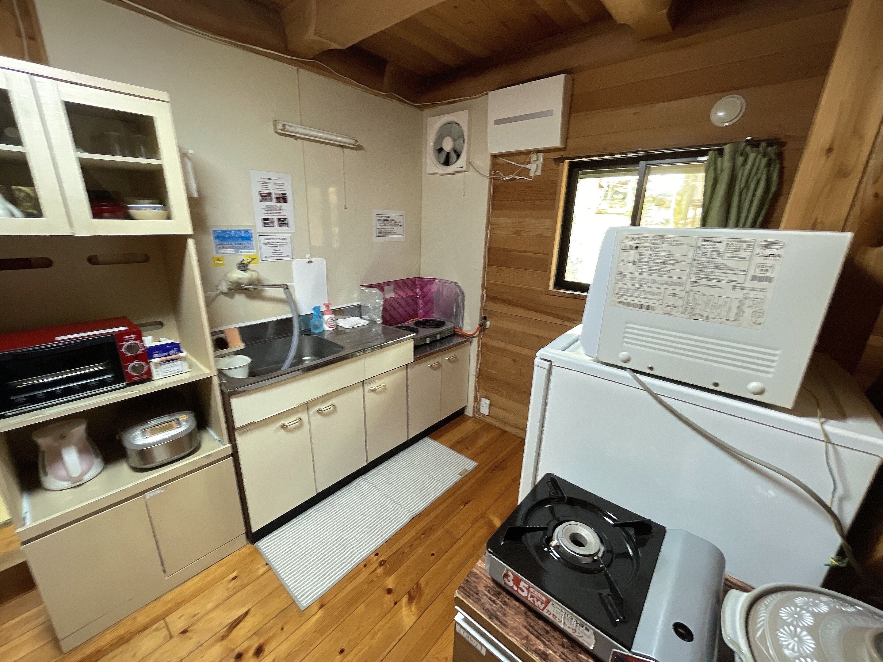 A compact kitchen with a microwave, sink, and a small refrigerator.