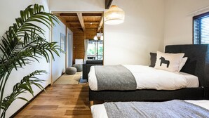 A bedroom with a bed, a large potted plant, wooden flooring, and a hanging light fixture. - Kurasako Onsen Sakura (Minamioguni)