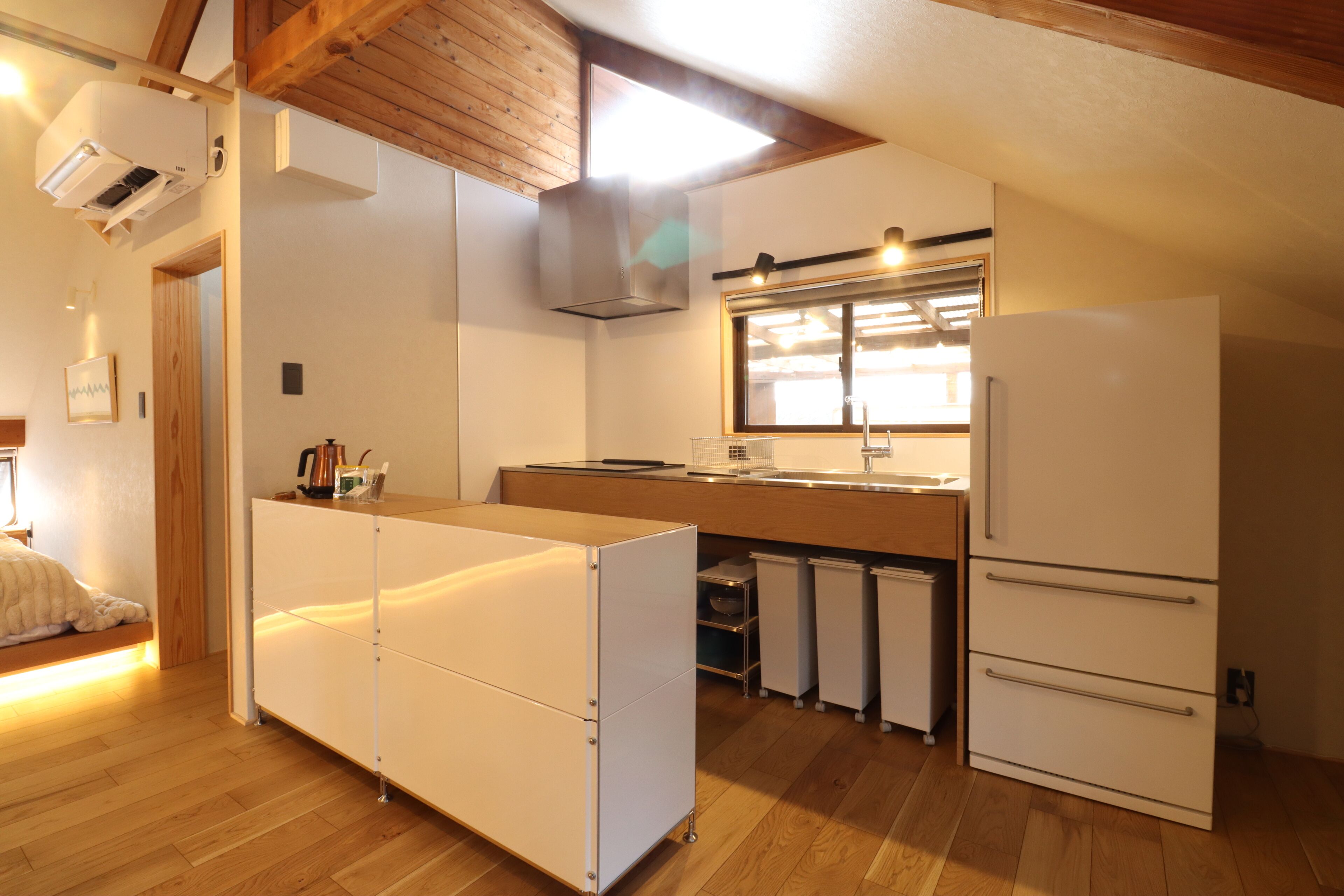 A modern kitchen with white cabinetry, a built-in oven, and a window above the sink.