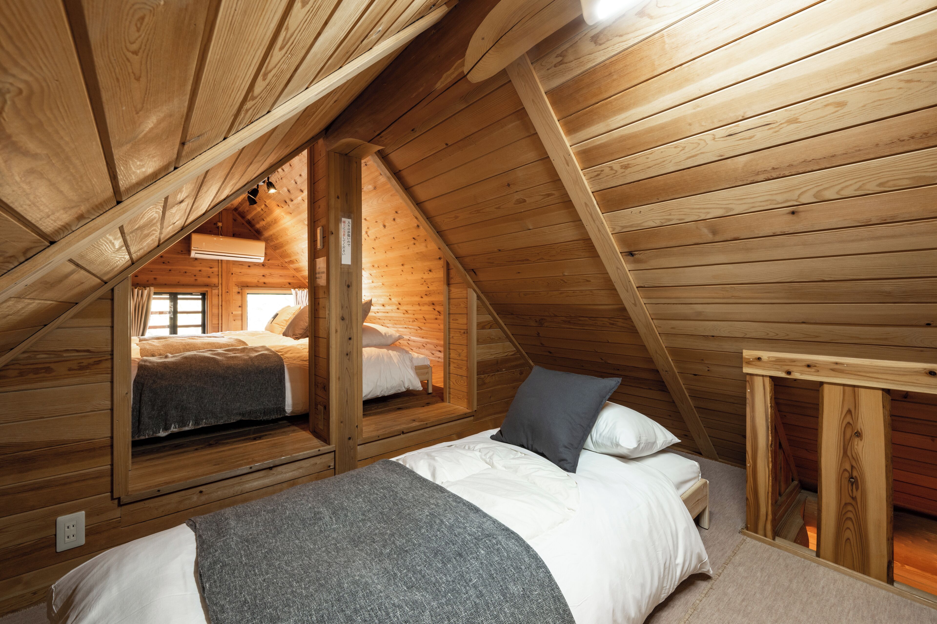 A cozy attic bedroom with a sloped ceiling, wooden beams, and a bunk bed.