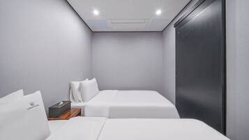A modern hotel room with two beds, a wooden nightstand, and a dark door.