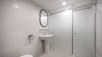A modern bathroom with a toilet, sink, and glass shower enclosure.