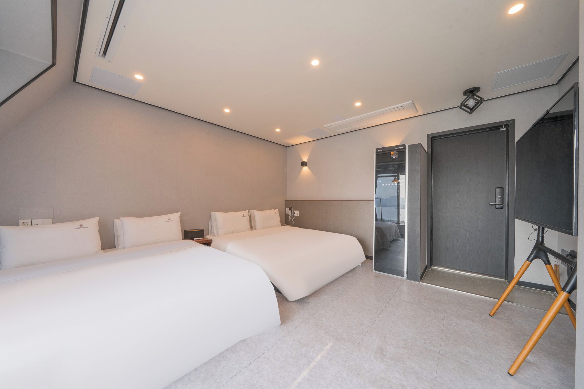 Una habitación de hotel moderna con dos camas, un espejo grande y una puerta que da a un baño.