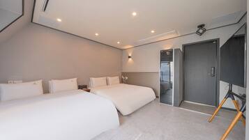 Una habitación de hotel moderna con dos camas, un espejo grande y una puerta que da a un baño.