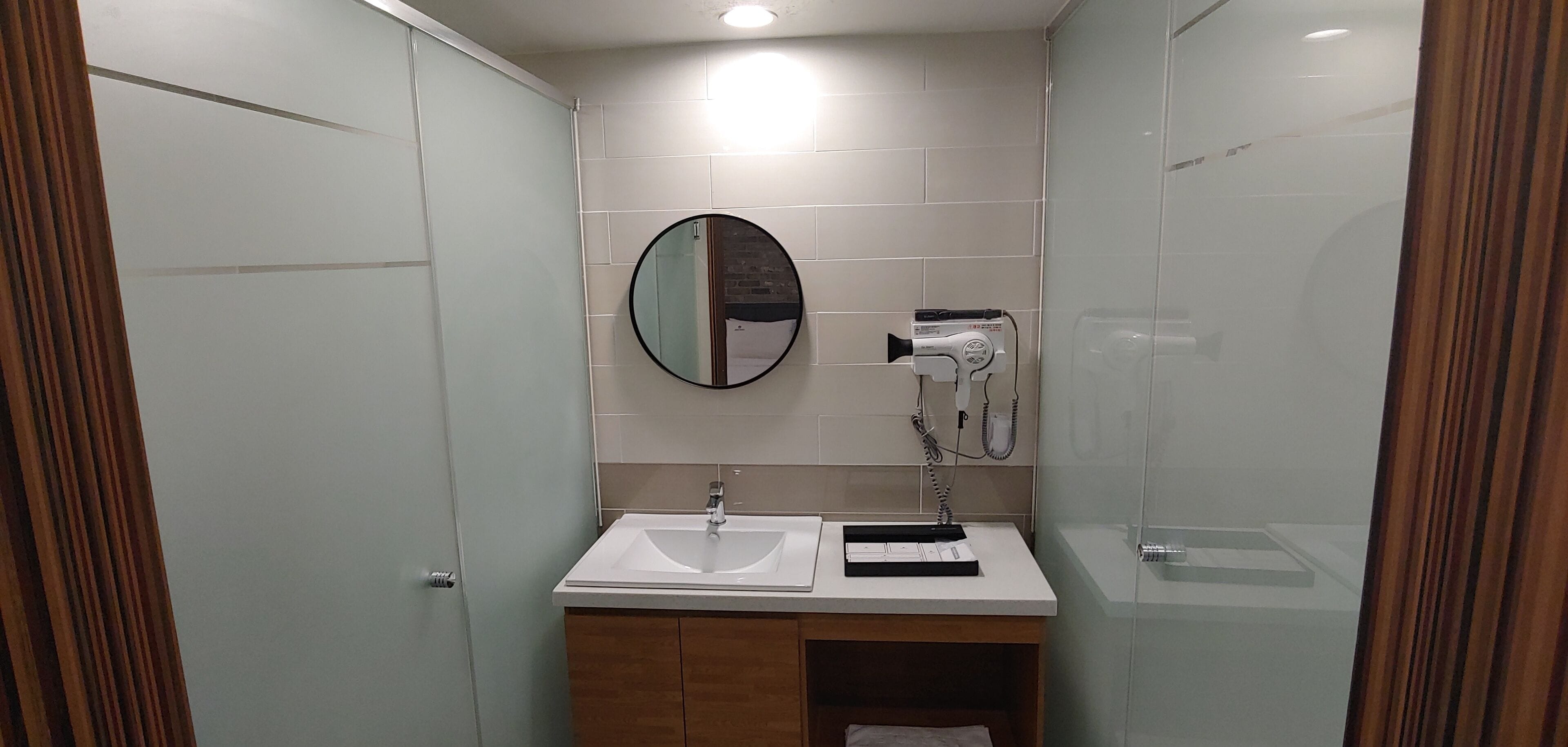 Un baño moderno con lavamanos, espejo y toallero blancos.