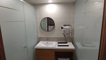 Un baño moderno con lavamanos, espejo y toallero blancos.