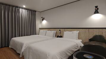 Una habitación de hotel con dos camas, un escritorio, una silla y una lámpara en la pared.