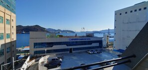 Un bâtiment moderne avec un espace de stationnement à l’avant, offrant une vue sur une étendue d’eau et sur des collines lointaines.