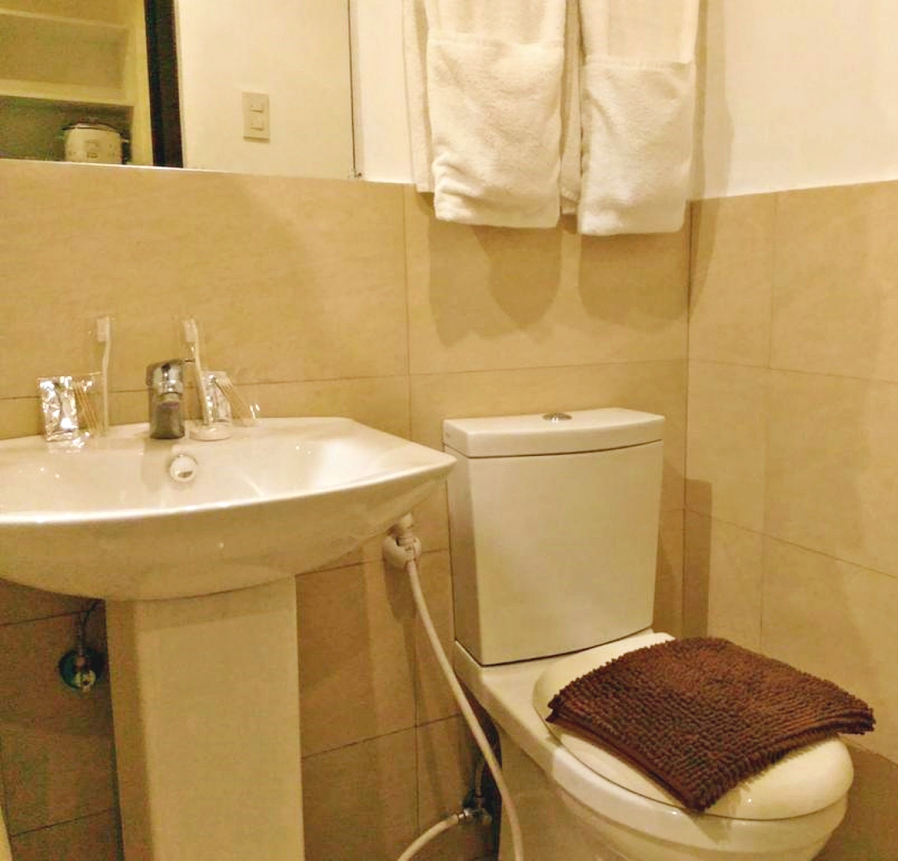 A bathroom with a white sink, toilet, and a towel hanging on the wall.