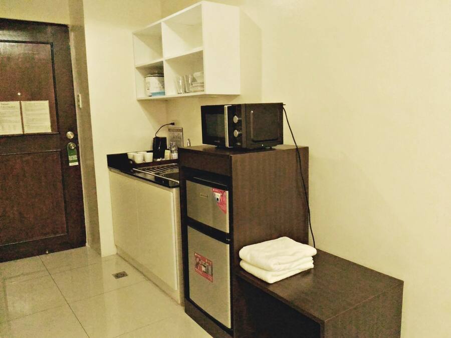 Una kitchenette compacta con microondas, estufa pequeña y pileta. Hay una toalla blanca sobre una mesada.