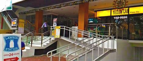 A multi-level shopping area with a Lawson Station sign, a Yellow Cab Pizza Co. sign, and a staircase with metal railings.