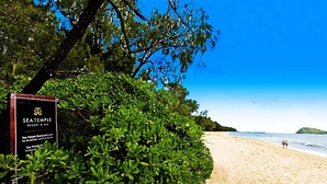 A beach with a sign for Sea Temple Resort & Spa, indicating it offers breakfast, lunch, and dinner.