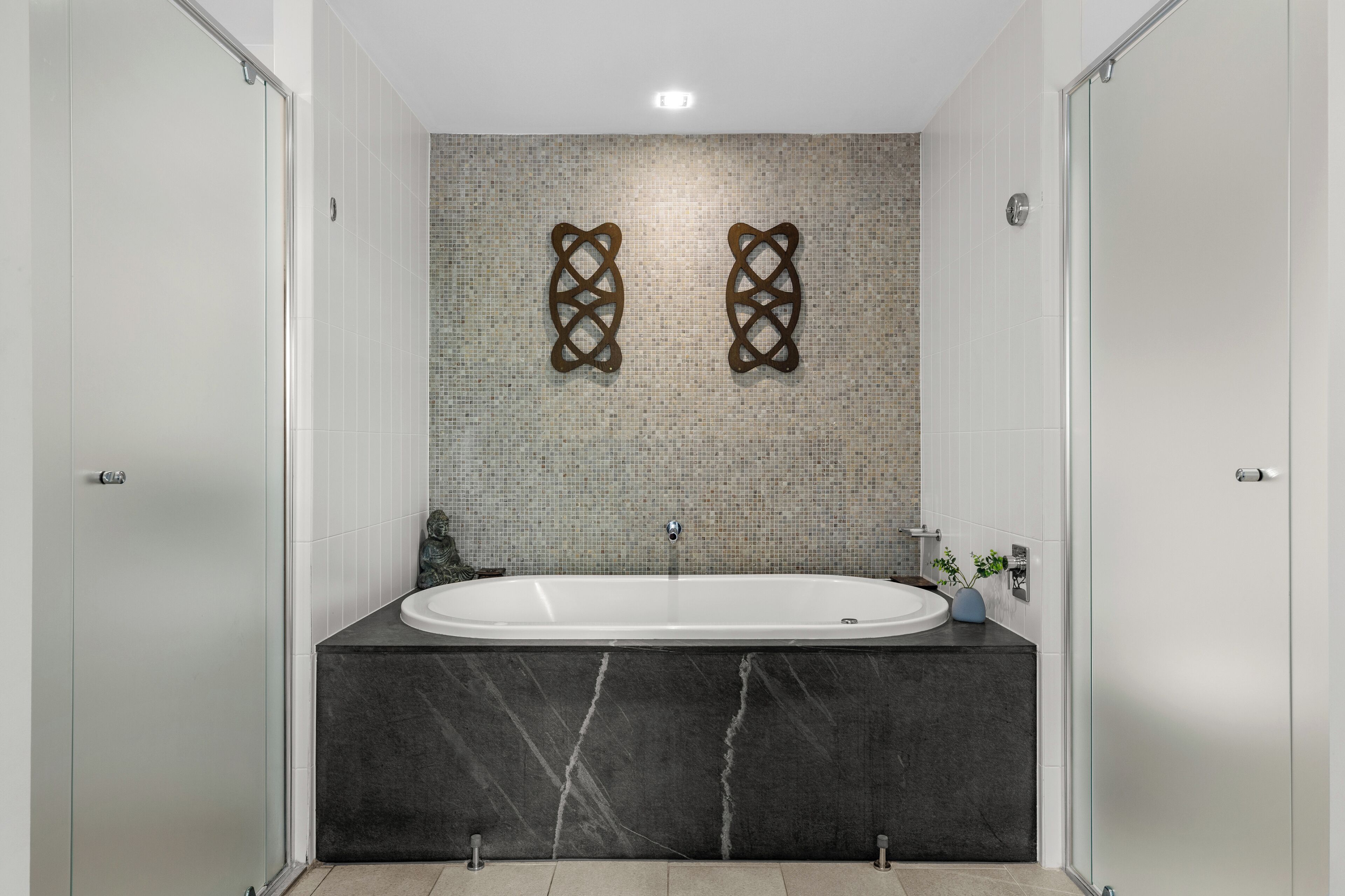 Une salle de bain moderne avec une baignoire sur pieds, un pare-feu en carreaux et un meuble-lavabo en marbre.