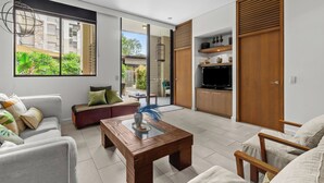 A modern living room with a sofa, armchairs, a coffee table, and a TV.
