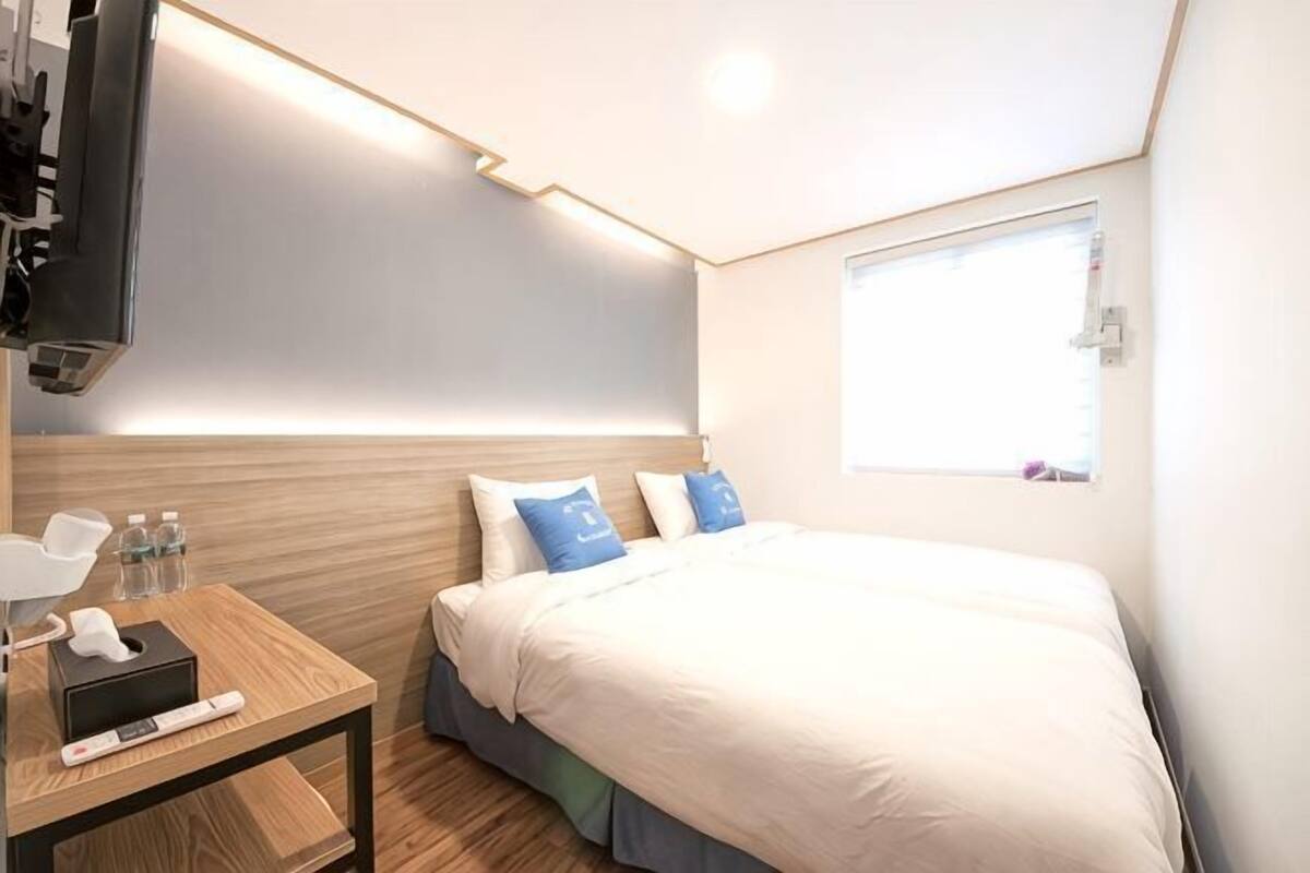 A modern hotel room with a bed, bedside table, and a television.