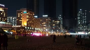A hotel with multiple floors and a casino sign, surrounded by high-rise buildings and a busy street with lights.