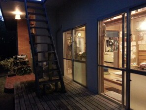 A wooden deck with a ladder leading to a glass door entrance. - OKINAWA MOTOBU GUESTHOUSE - Hostel (Motobu)