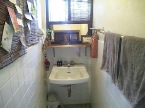 A small bathroom with a sink, a mirror, a towel rack, and a window with blinds. - OKINAWA MOTOBU GUESTHOUSE - Hostel (Motobu)