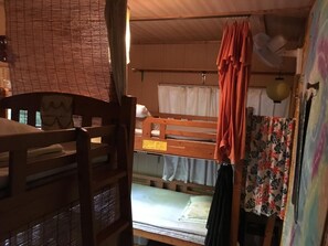 A bunk bed room with a wooden desk and a chair, a window with blinds, and a hanging fan. - OKINAWA MOTOBU GUESTHOUSE - Hostel (Motobu)