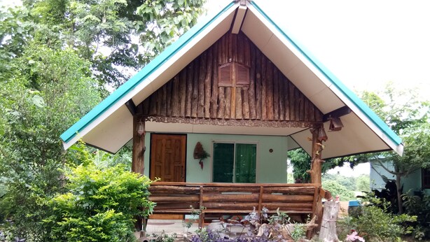 Une cabane rustique en bois, dotée d’un toit en pente, d’un porche en bois et d’une fenêtre avec des volets.