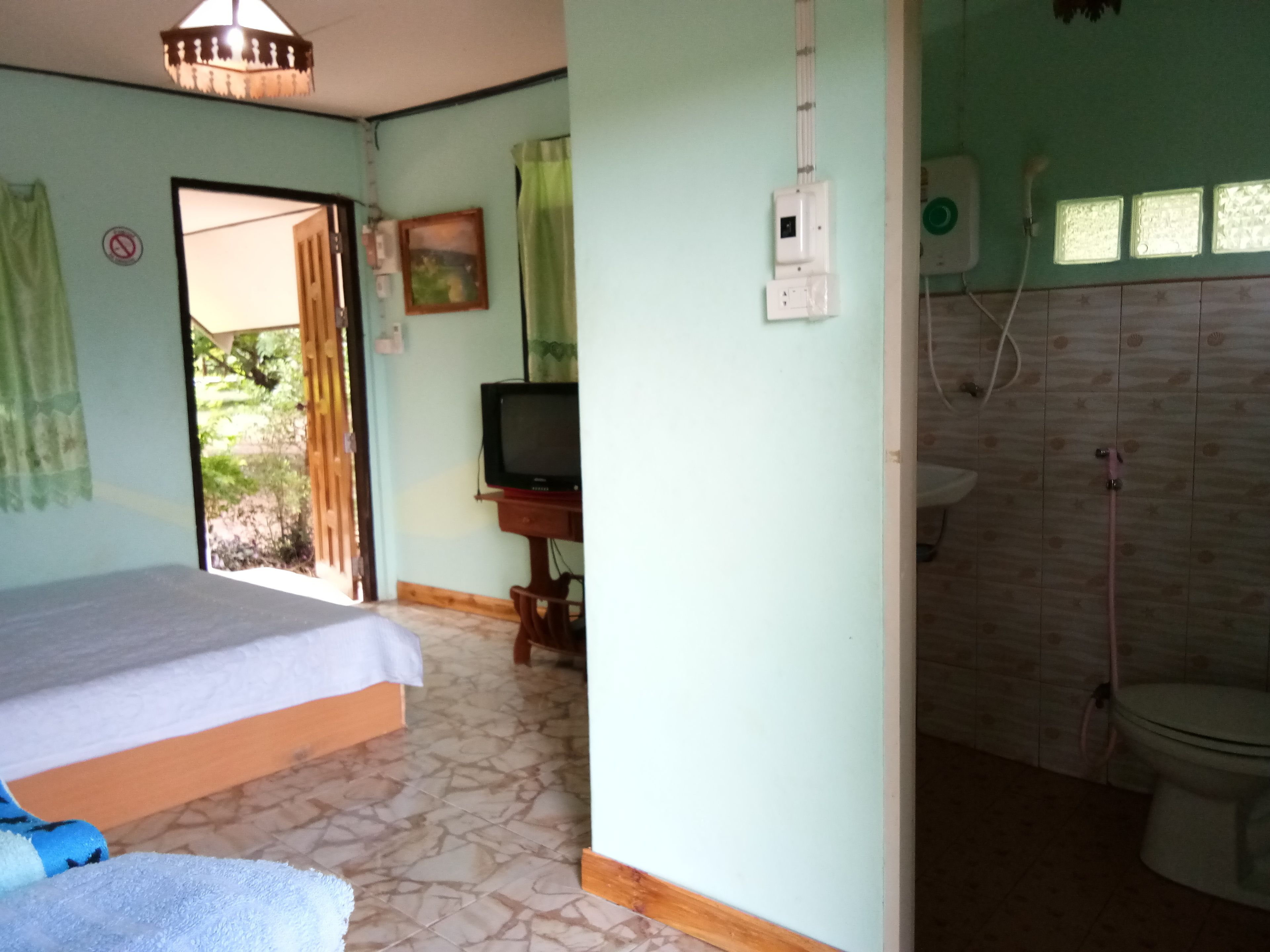 A bedroom with a bed, a television, and a bathroom with a toilet and shower.