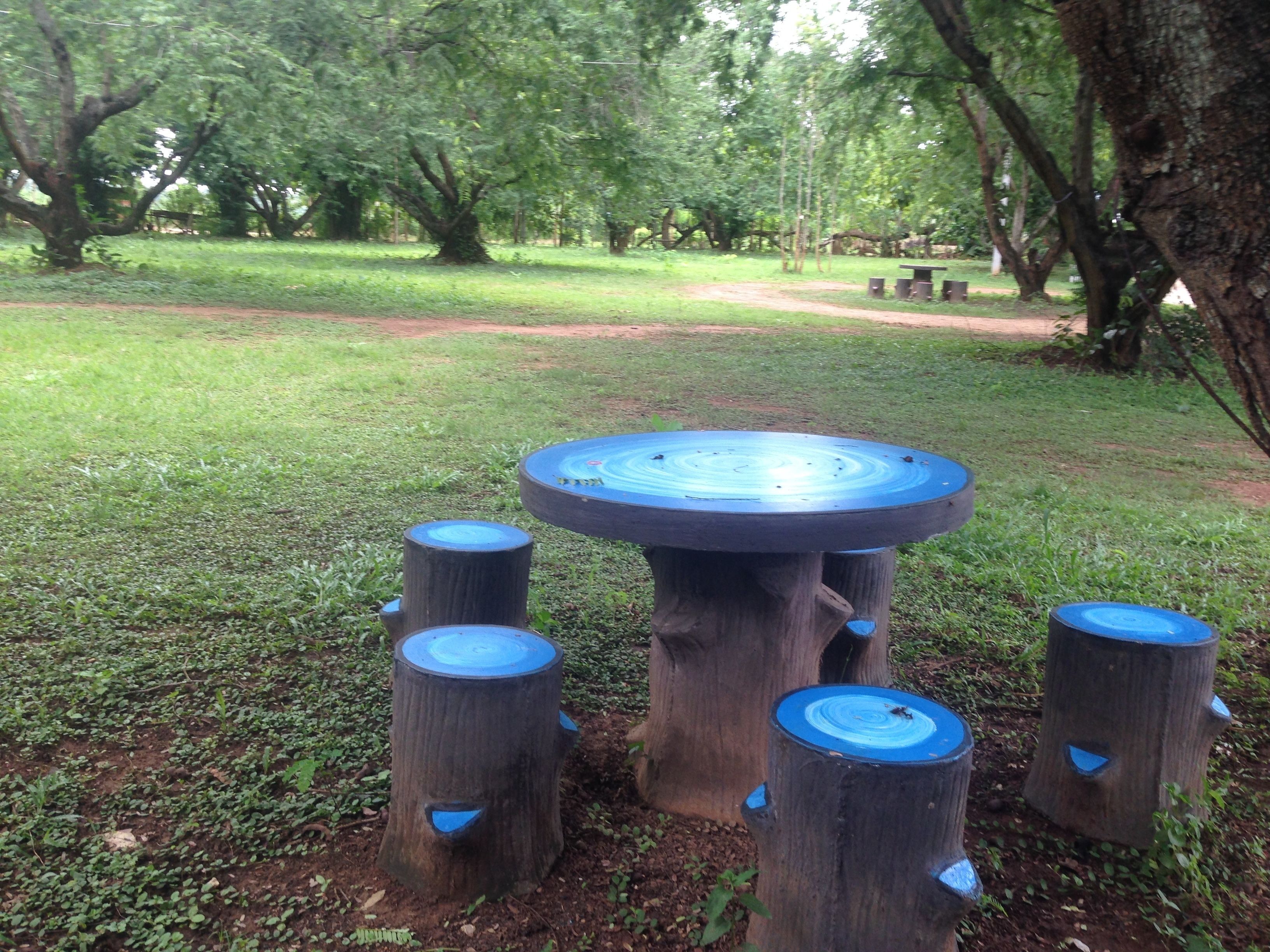 A round wooden table with a blue top surrounded by four matching stools.