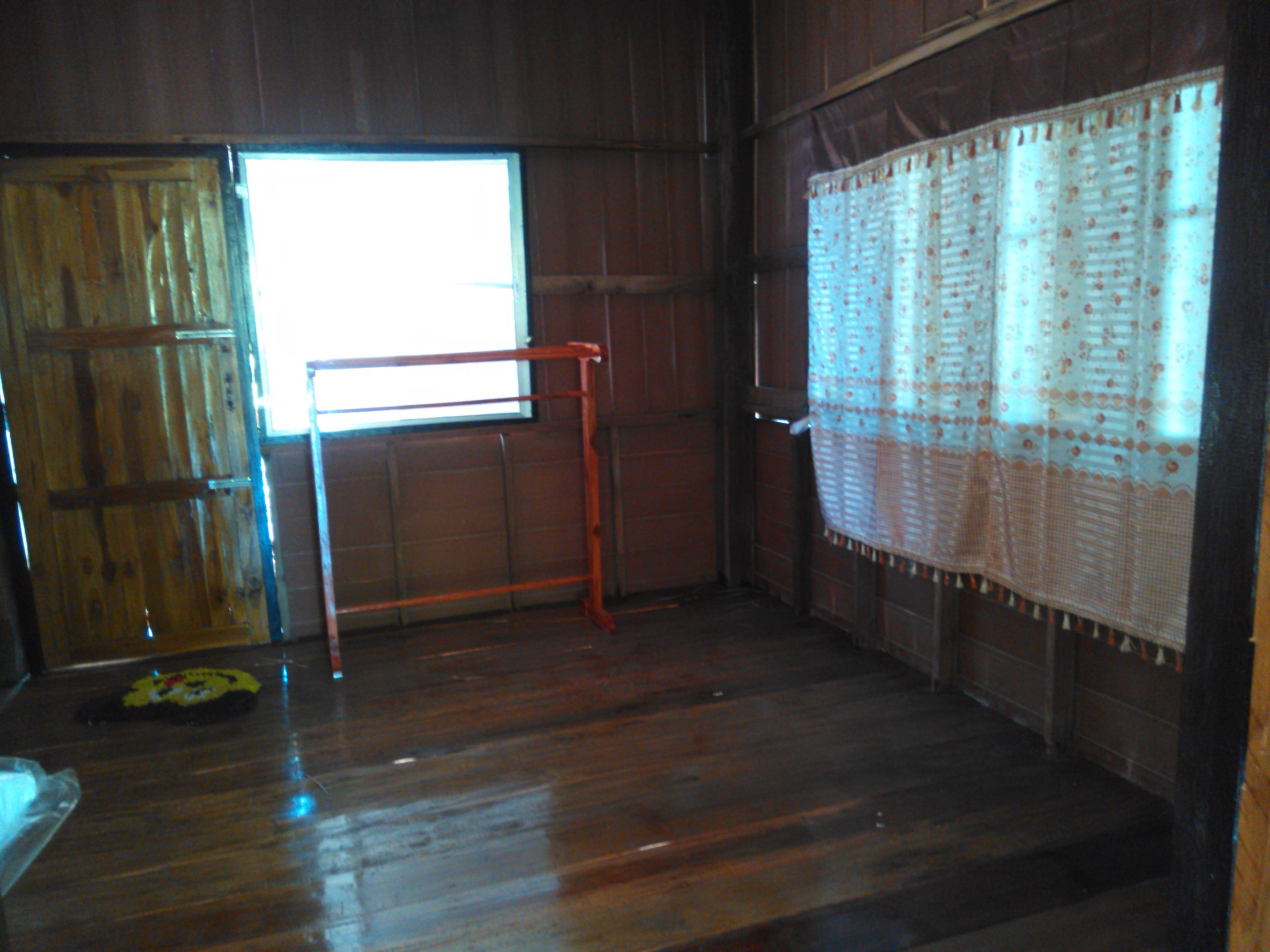 Una habitación con paredes de madera, una ventana con vistas, un perchero de metal y una cortina estampada.