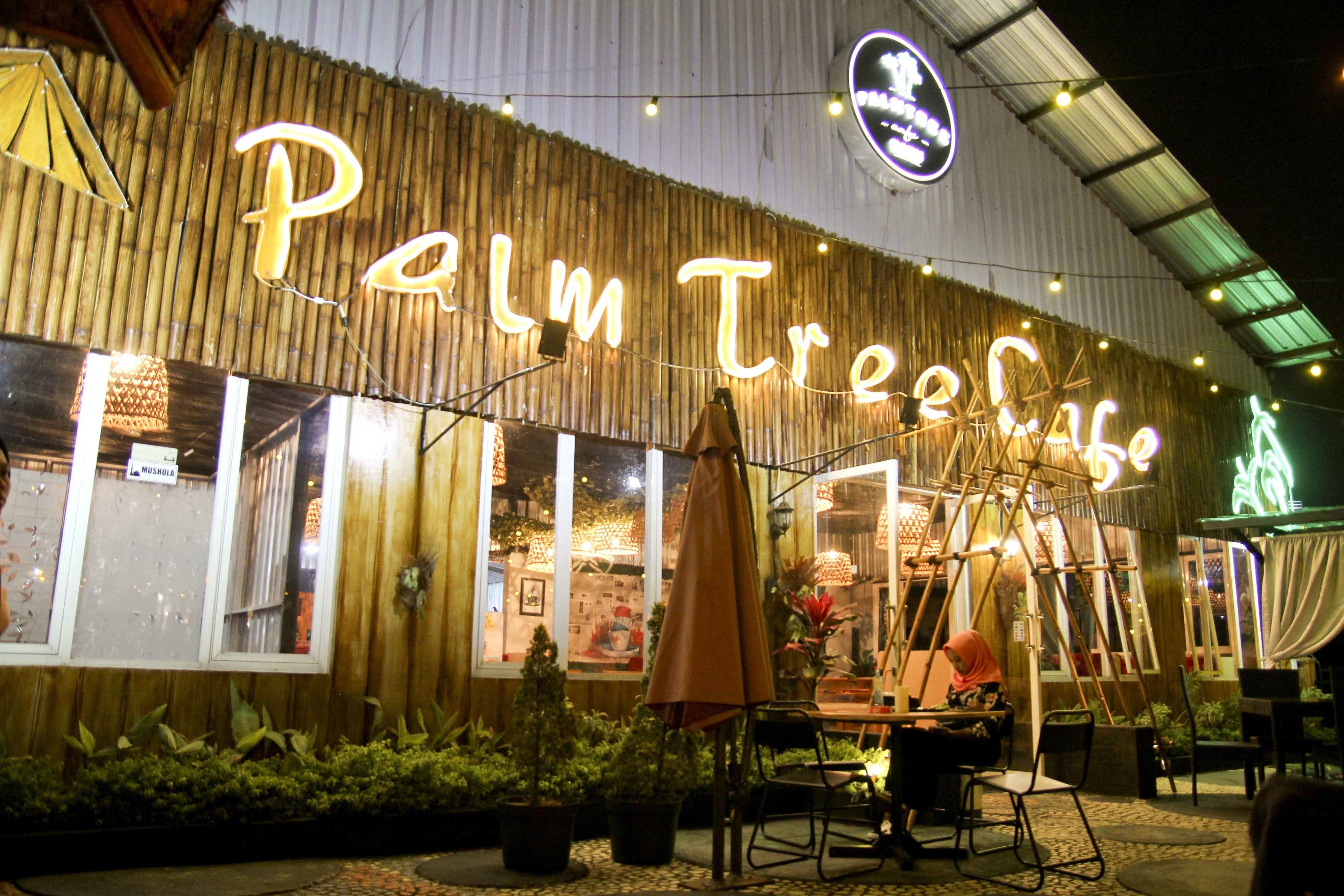 A restaurant named "Palm Tree Cafe" with outdoor seating and string lights.