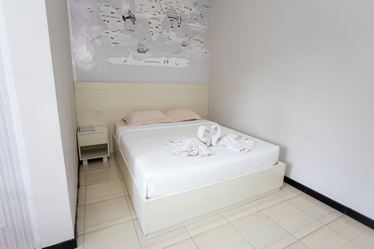 Una habitación de hotel con una cama, una mesita de noche y un mapa en la pared.