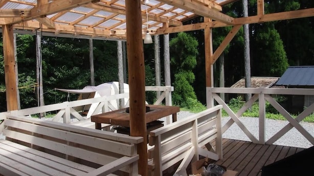 Eine Holzterrasse mit einer Pergola, Bänken und einem Tisch.