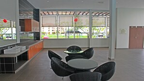 Une cuisine moderne avec un comptoir et un évier, un coin repas avec une table ronde et des chaises noires, et de grandes fenêtres offrant une vue sur l’extérieur.