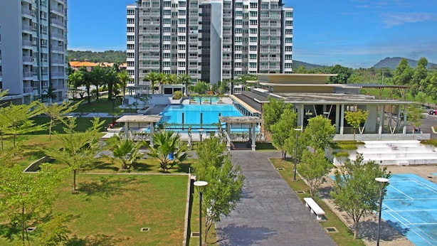 Un hôtel moderne doté d’une grande piscine, de nombreux balcons et d’une végétation luxuriante.