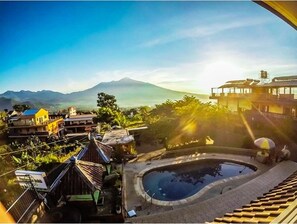 A residential area with a swimming pool, houses, and a mountain in the background. - Villa Panderman Indah (Batu)