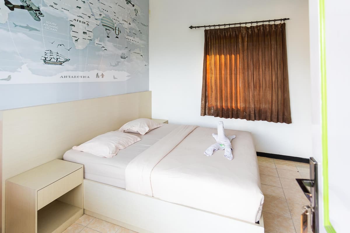 Una cama bien hecha con una almohada, una mesita de noche y un mapa de pared.