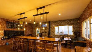 A cozy restaurant with a long wooden bar, brick walls, and hanging light fixtures. - Villa Panderman Indah (Batu)