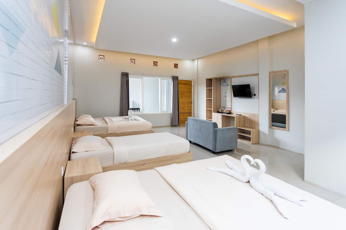 Habitación de hotel con tres camas, un sofá, un televisor y un espejo.