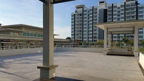 A rooftop terrace with a view of high-rise residential buildings, a covered seating area, and a small garden. - Homestay Signature Suite (Sandakan)