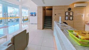 A hotel lobby with a reception desk, a staircase, and a view of the outside. - My Inn Hotel Kota Samarahan (Kota Samarahan)