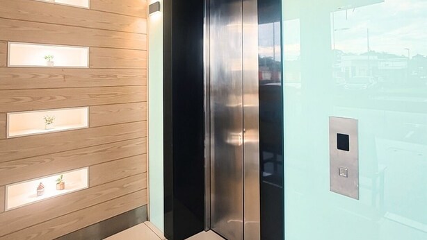 A modern elevator with a metallic finish, a wall-mounted light panel, and a small control panel on the wall. - My Inn Hotel Kota Samarahan (Kota Samarahan)