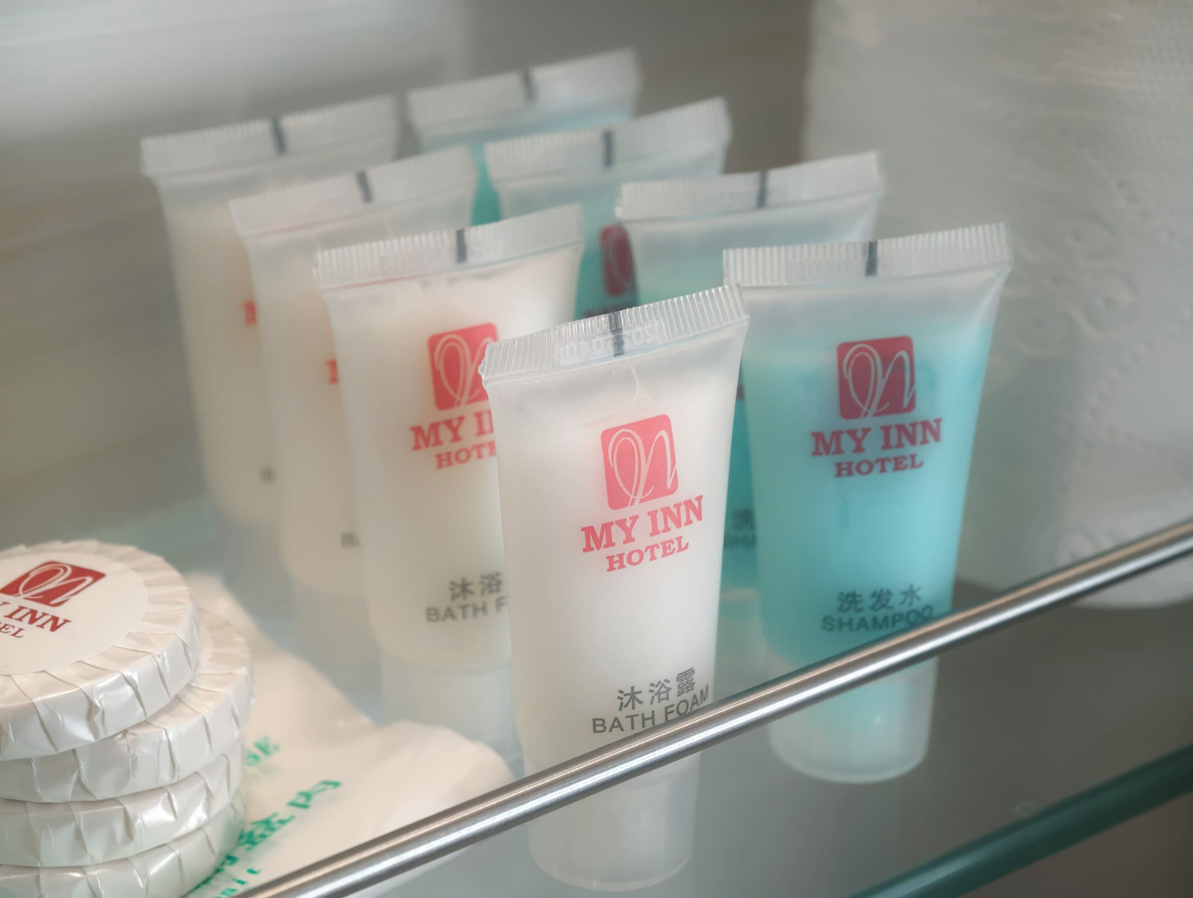 Estante de hotel con artículos de baño, incluyendo espuma de baño, champú y un recipiente con sales de baño.