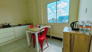A small kitchen with a table and chairs, a window with a city view, and a cabinet with water bottles. - My Inn Hotel Kota Samarahan (Kota Samarahan)