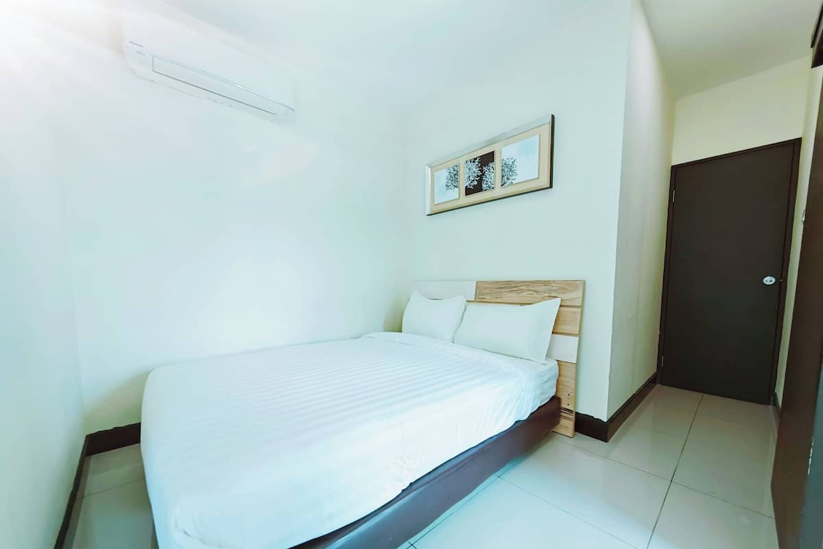 Quarto de hotel com uma cama, um quadro pendurado na parede e uma porta.
