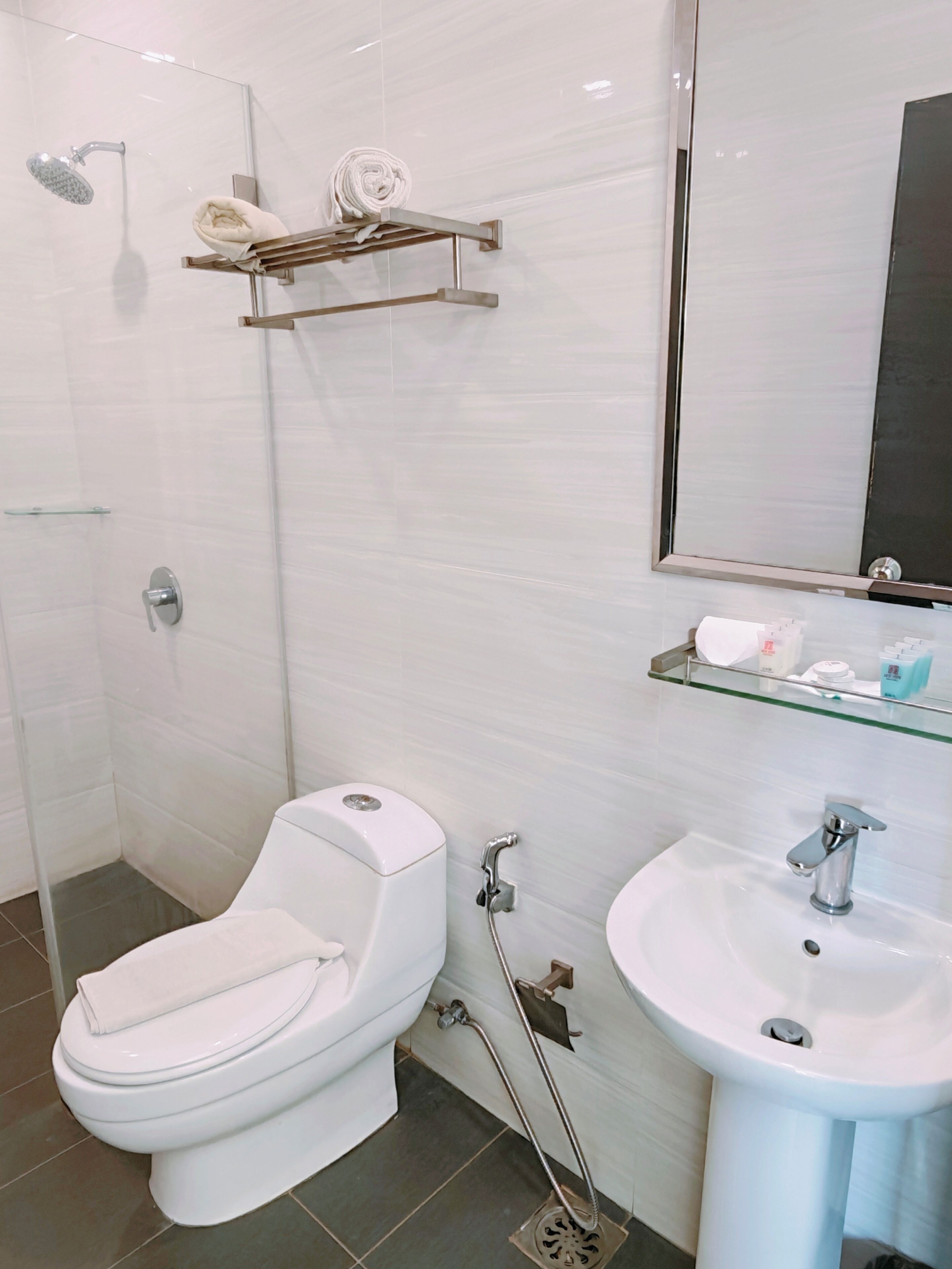 A modern bathroom with a toilet, bidet, glass shower enclosure, and a sink with a mirror.