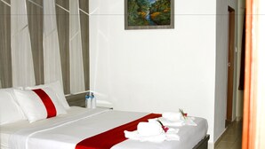 A hotel room with a neatly made bed, a painting on the wall, and a door to the right. - Paradise Hotel (Tanjung Pinang)