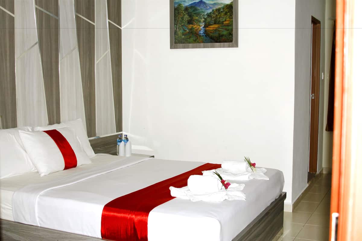A hotel room with a neatly made bed, a painting on the wall, and a door to the right.